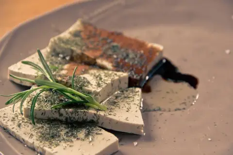 Pokrojone w kostkę tofu, posypane ziołami, z gałązką rozmarynu. Idealne tofu dla niemowlaka, zdrowe i smaczne.
